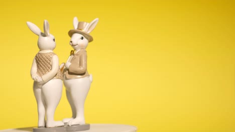 figurines easter bunnies on a yellow background rotate in a circle. easter holiday