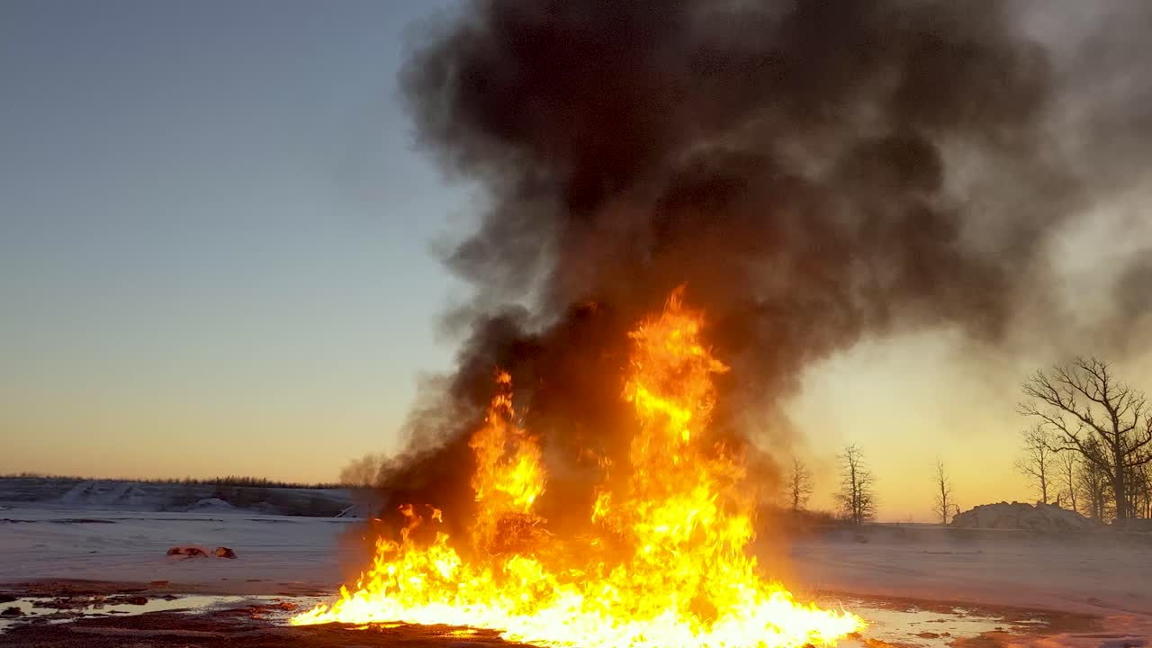 Huge fire burns up an oil spill leaving huge thick black clouds of smoke drifting across the sky