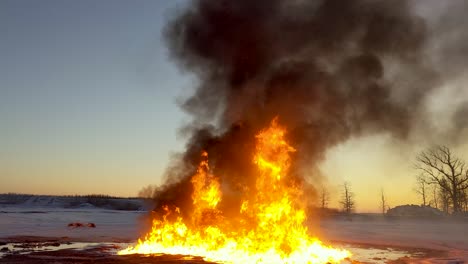 huge fire burns up an oil spill leaving huge thick black clouds of smoke drifting across the sky