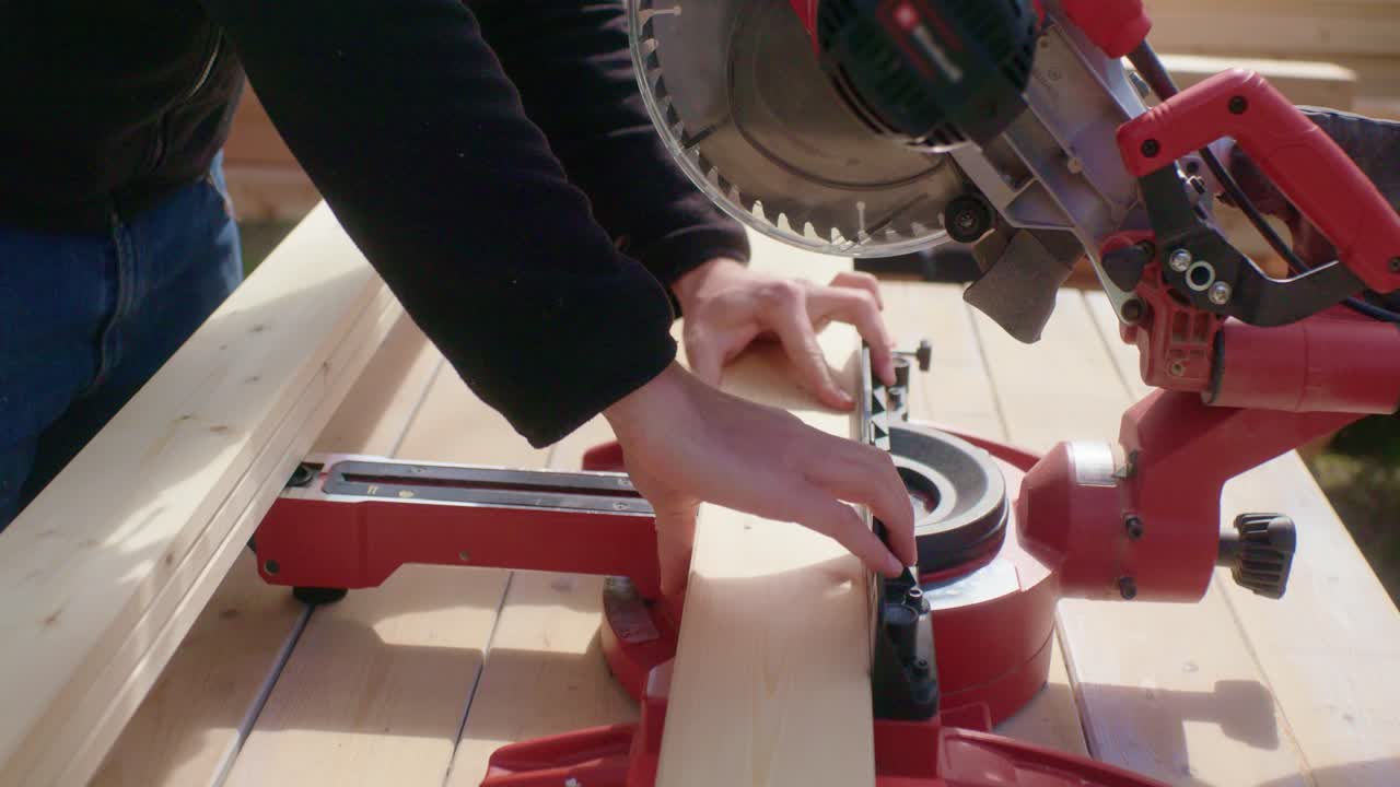 L'artigiano sega il pezzo di legno sottile a misura