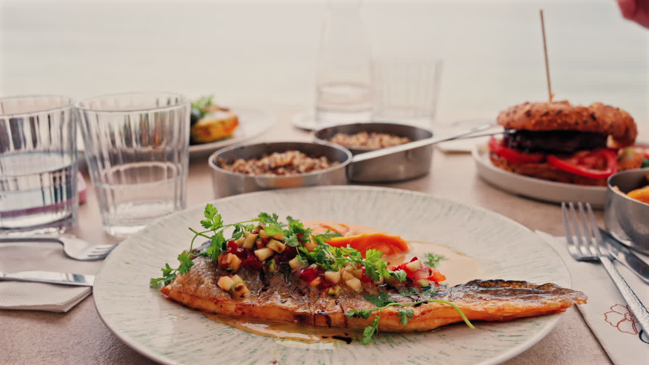 Close up of grilled fish with a sweet potato puree and a sauce on a white plate on a table at a restaurant