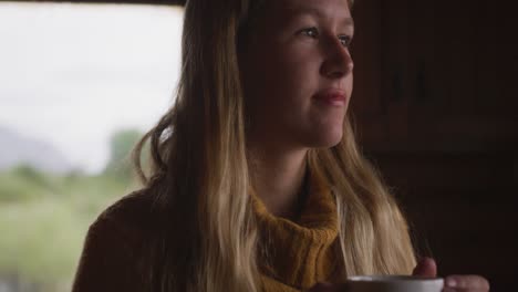 caucasian woman spending time at home, drinking a beverage, looking at the window