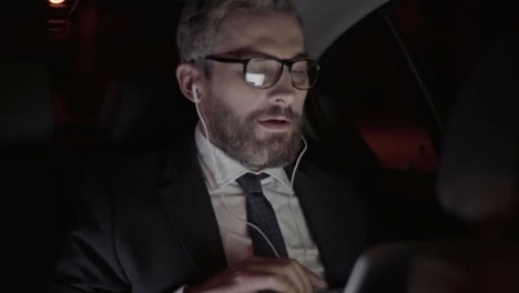 businessman with gray hair, glasses and stylish clothes greets on a video call while traveling by car