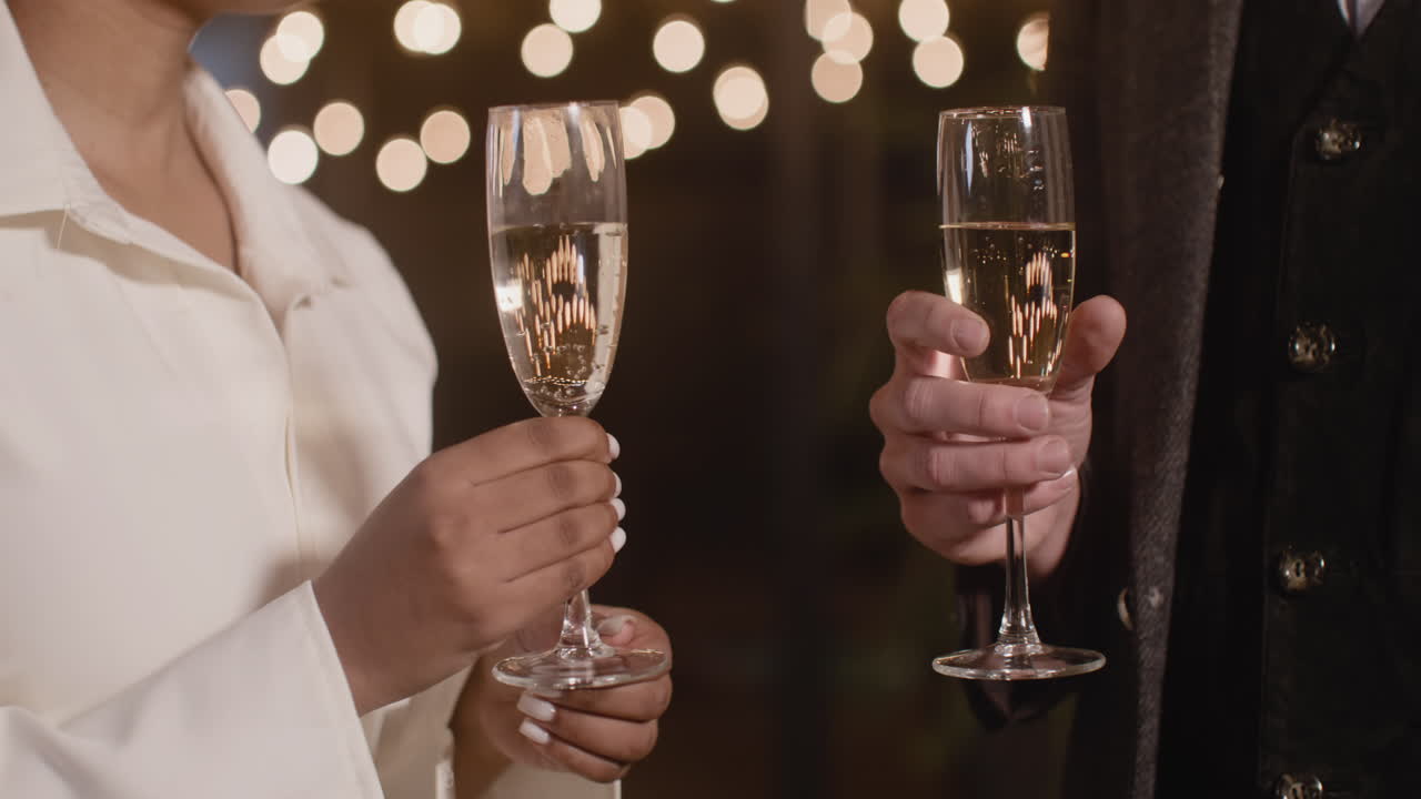 cerca de una pareja multiétnica irreconocible brindando con copas de champán en la fiesta de nochevieja