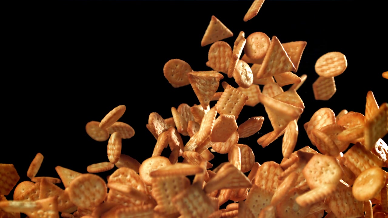Cracker salati assortiti in caduta e risalita al rallentatore su sfondo nero