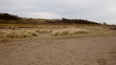 Mirando-Hacia-El-Interior-A-Través-De-Las-Dunas-De-Arena-Marram-Hierba-Con-El-Camino-Costero