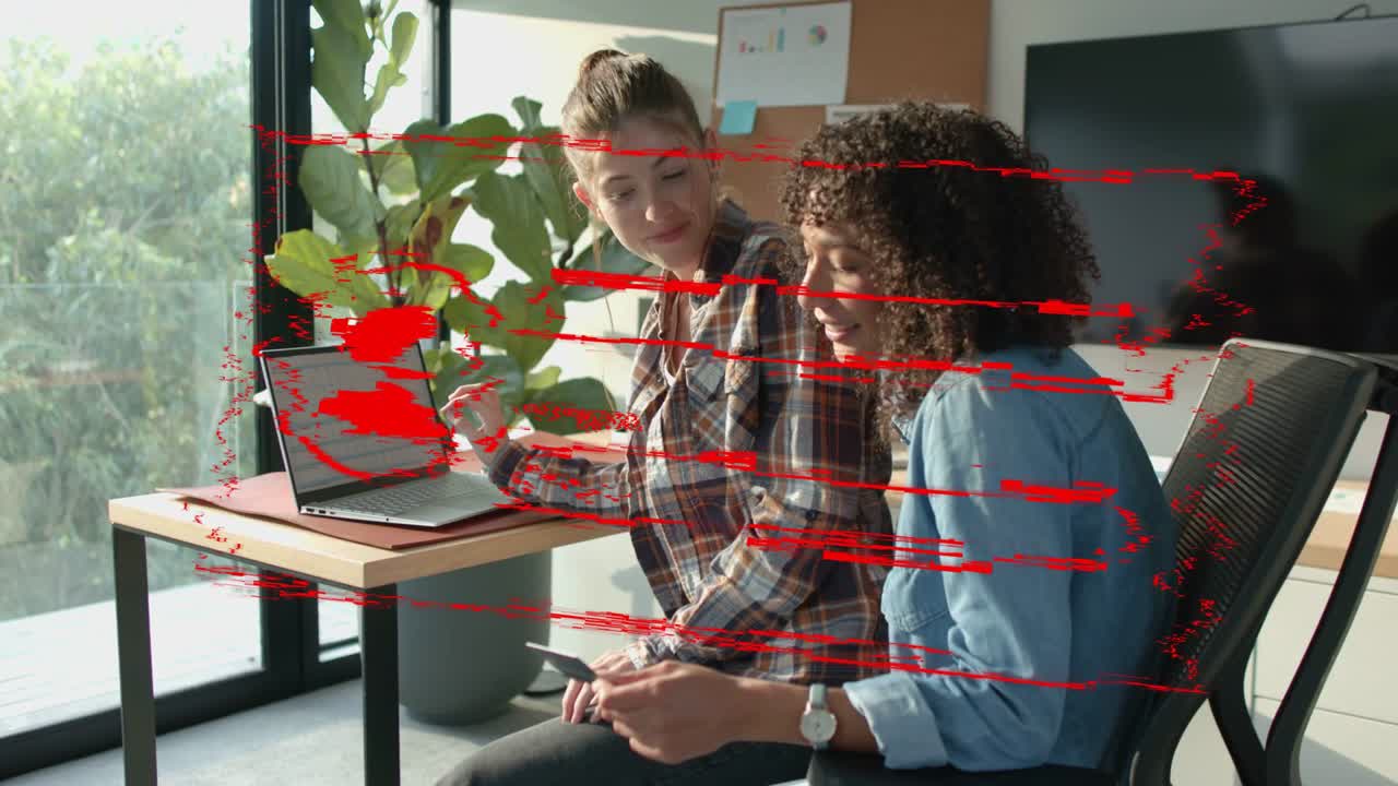 Office duo typing on laptop, laughing and leaning as red login overlay aligning for shared account