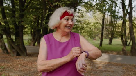 Senior-sport-runner-woman-using-smart-watch,-tracking-distance,-checking-pulse-after-fitness-workout