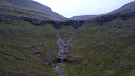 Small-waterfalls-falling-from-cliffs-and-converging-in-valley-in-Bordoy,-Faroe-Islands