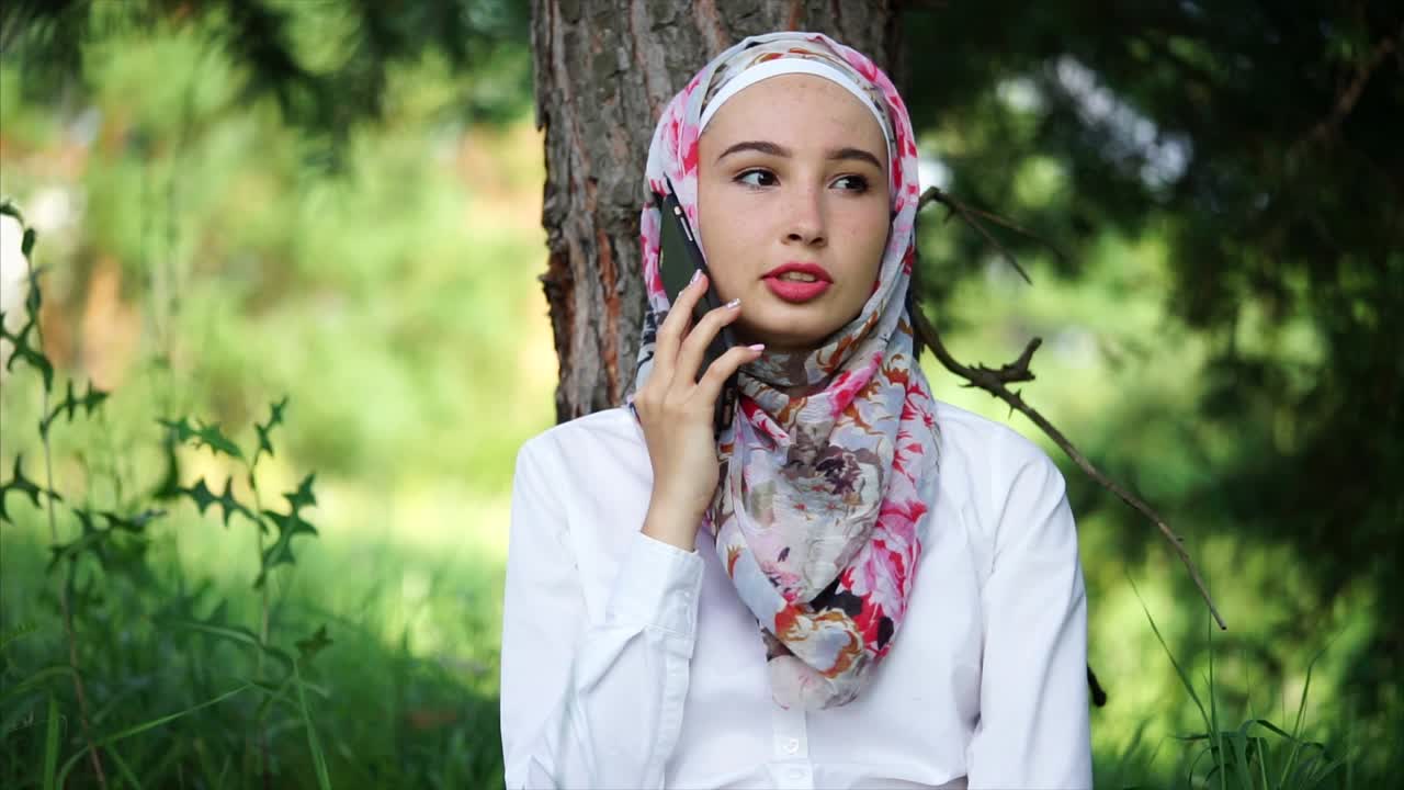Young Woman Talking on Phone in a Park