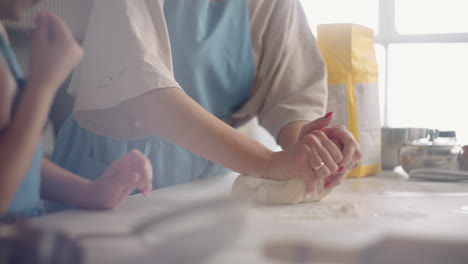 una mujer está enseñando a su hija en edad preescolar a amasar la masa para pan o pastel vista de primer plano