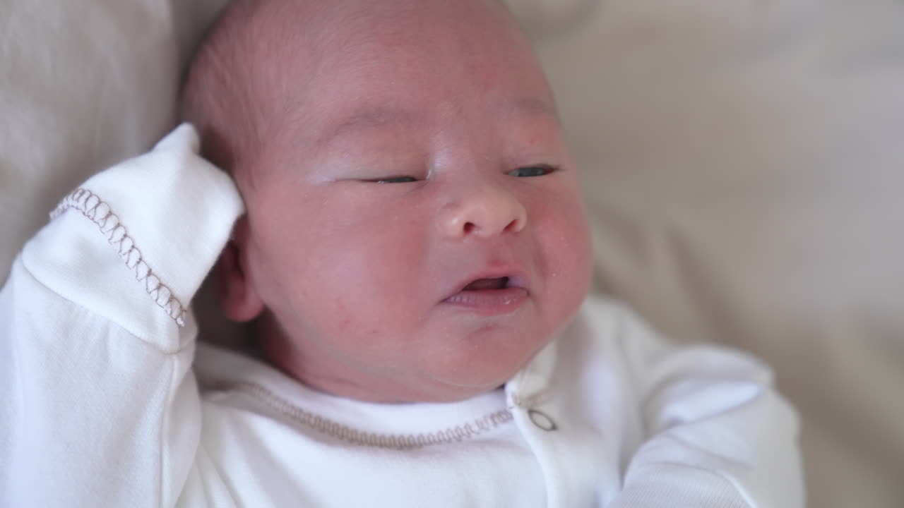 Face of adorable newborn baby. Portrait of healthy cute infant child boy on the bed at home. Happy family relationship and newborn baby. Close-up.