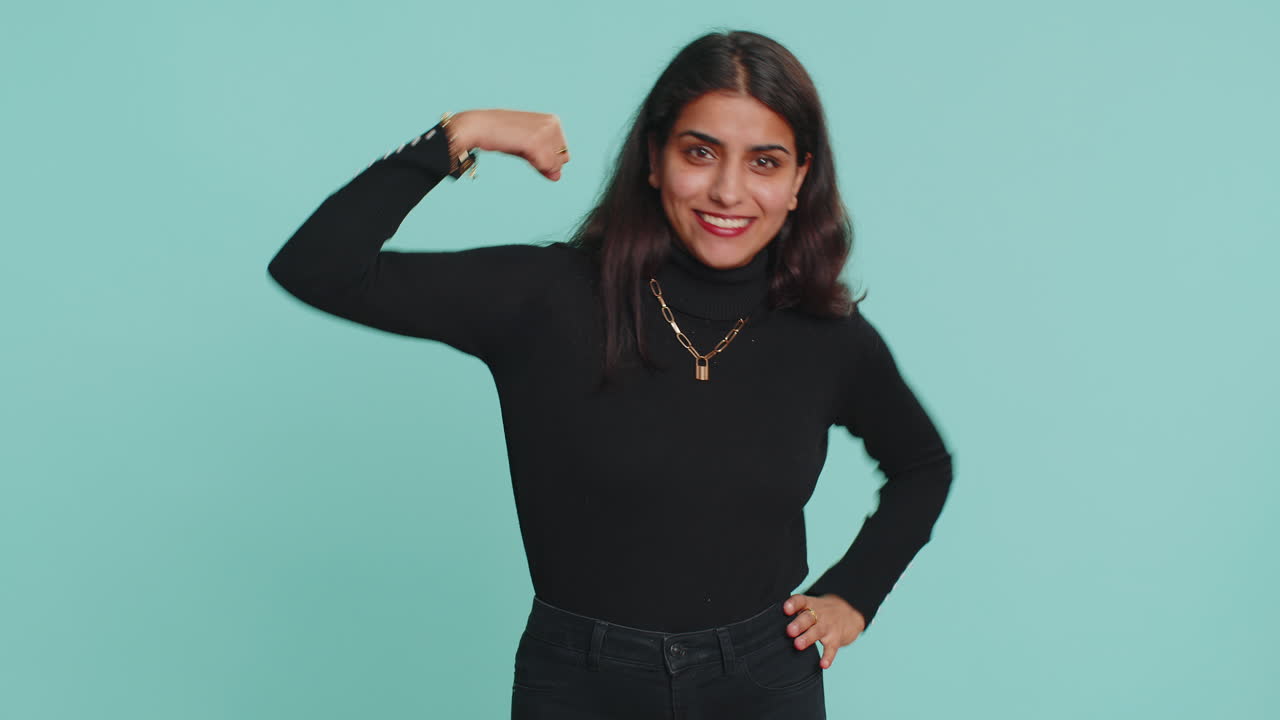 Fit sporty indian woman showing biceps and looking confident, feeling power strength success win
