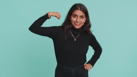 mujer india en forma mostrando bíceps y pareciendo confiada, sintiendo poder fuerza éxito ganar