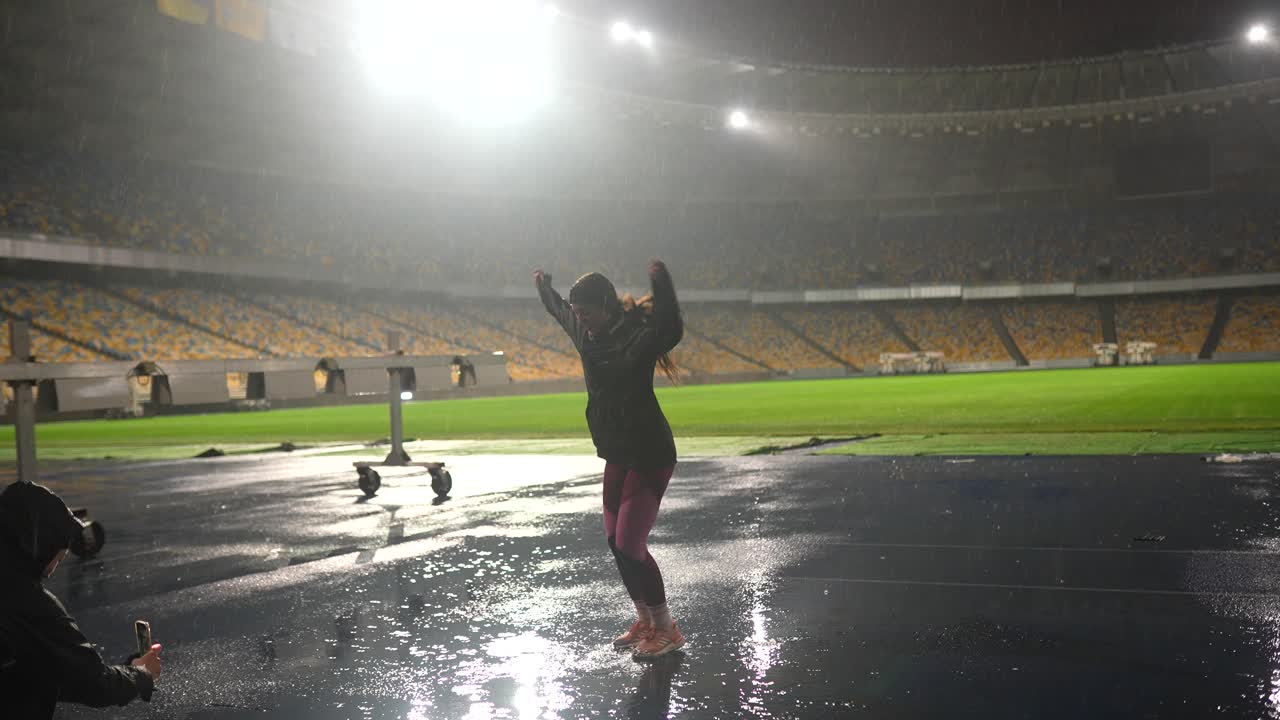 비가 오는 축구 경기장에서 춤을 추는 여자