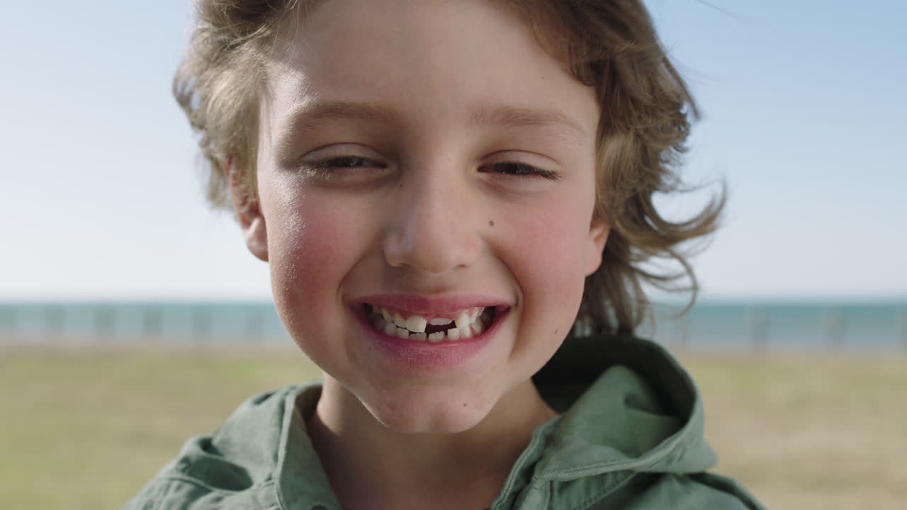 retrato en primer plano de un lindo niño caucásico sonriendo alegremente a la cámara disfrutando de un día de diversión en el parque de la playa costera