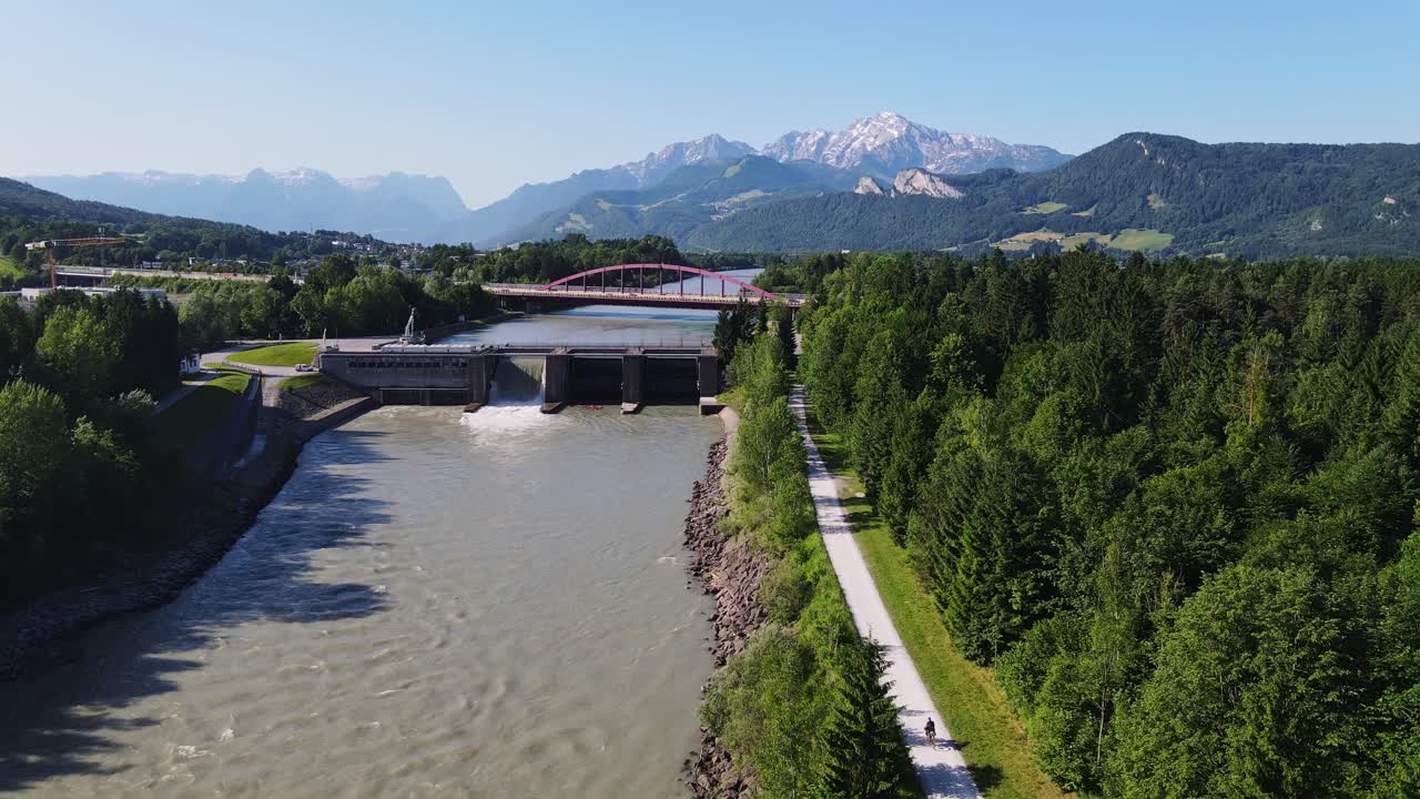 Drone of Kraftwerk Urstein dam over River Salzach with a cyclist passing nearby
