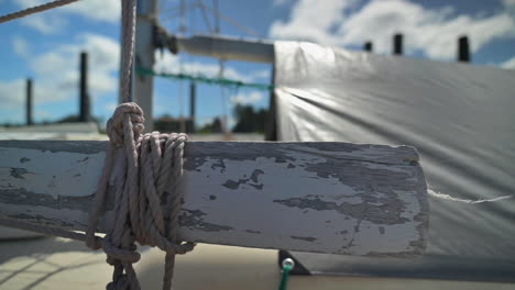 rope tied on horizontal wooden part of a sailing boat - close up, slider right