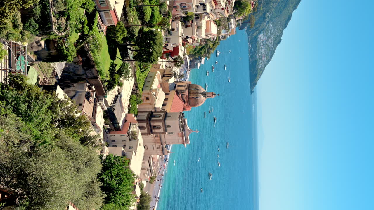 Street scape of Positano, located on the Tyrrhenian sea coast, Italy. Rows of residential buildings, church, greenery, boats in the distance. Vertical view