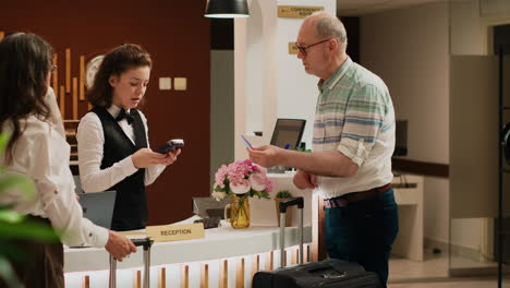 senior man paying for hotel room