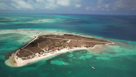 tropical island surrounded by clear blue water, two boats anchored nearby