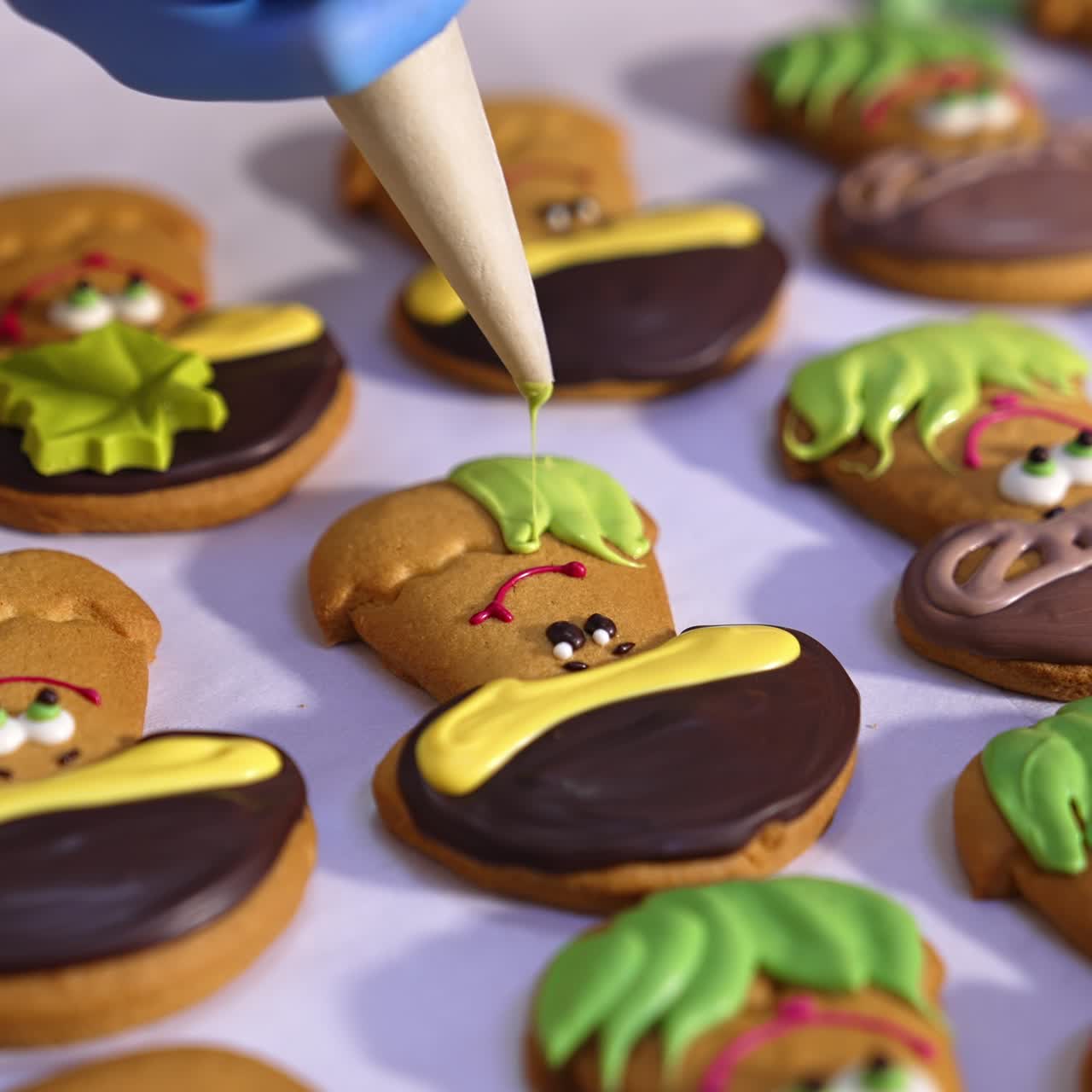 Cookies production in confectionary factory. Hands in gloves decorate biscuits in the shape of mushrooms with creamy decorations. Close up