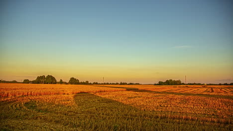 shadows of a rolled bale of hay and people working stretch into the farmland at sunset - time lapse