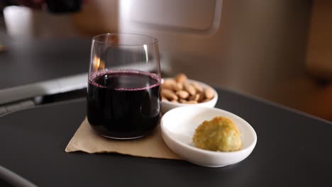 pasajero disfrutando de nueces y vino en la bandeja del avión