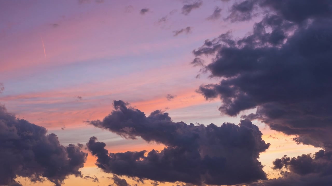 Purple, pink and blue clouds flowing as the sun sets in Chicago on a summer evening.