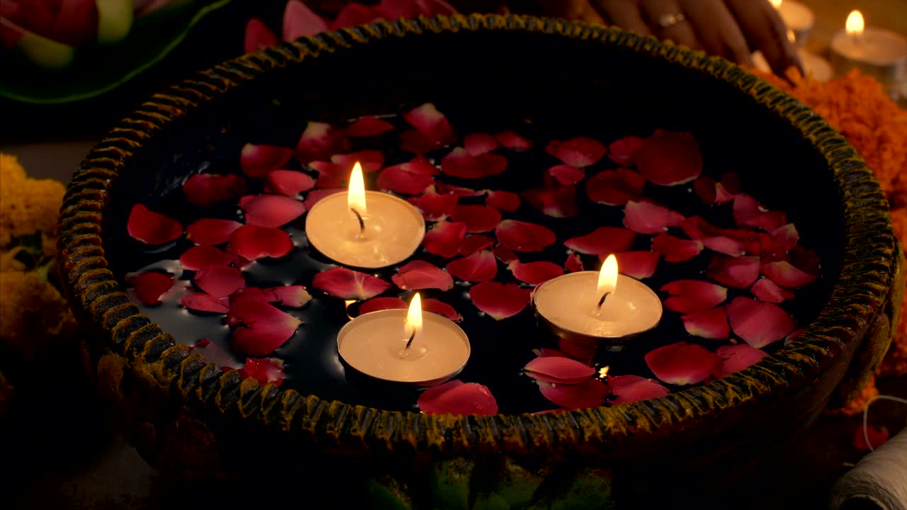 Diwali decoration - woman decorating her house with floating candles in a bowl / urli