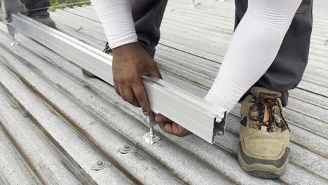 a worker adjusts a profiled aluminum rail to support a photovoltaic panel