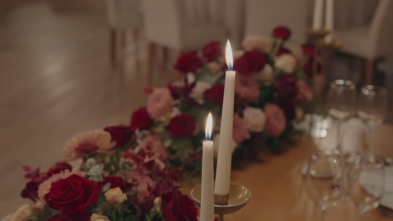 따뜻한 촛불이 풍성한 장미와 파스텔 톤 웨딩 플라워 옆에서 빛나고 있어요.