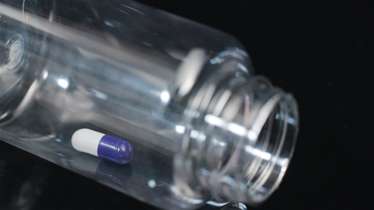 píldora médica única en botella pequeña girando sobre fondo negro