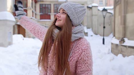 Woman-tourist-looking-to-camera,-waving-hi,-hello,-welcome,-goodbye-gesture-sign,-outdoors-in-winter