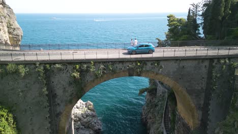 cinematic drone shot over bridge with tourists looking at sea