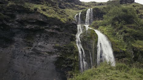 Hermosos-Arroyos-De-Una-Pequeña-Cascada-Corren-Sobre-Un-Acantilado-Marcado-Con-Ramitas-De-Hierba