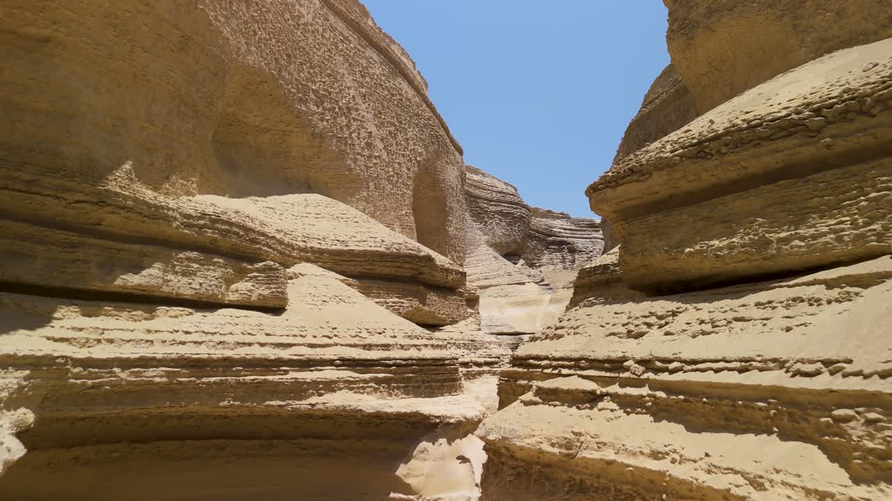 Striking sandstone canyon walls and winding passageways at Canyon of the Lost in Ica Peru under a clear blue sky - aerial flying through