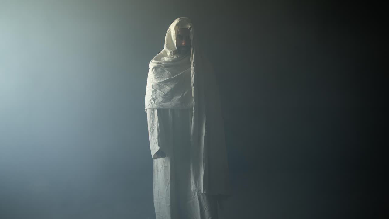 The resurrected Jesus Christ standing inside the tomb in bright, dramatic, contrast of darkness and holy light as representation of the Easter Sunday resurrection in cinematic slow motion.