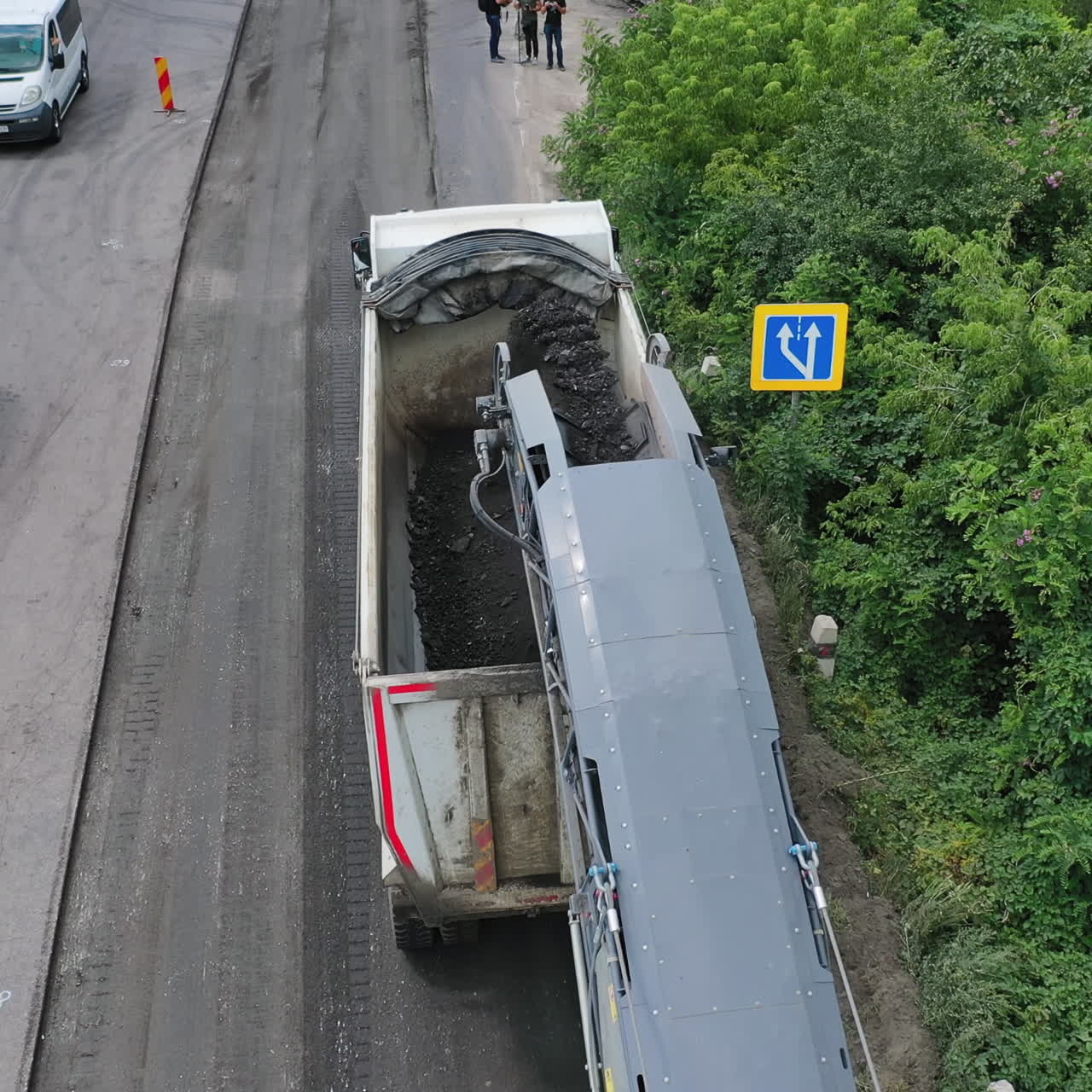 Heavy machinery at roadworks. Special machinery loading truck with asphalt on the road. Reconstruction on the highway. Aerial view.