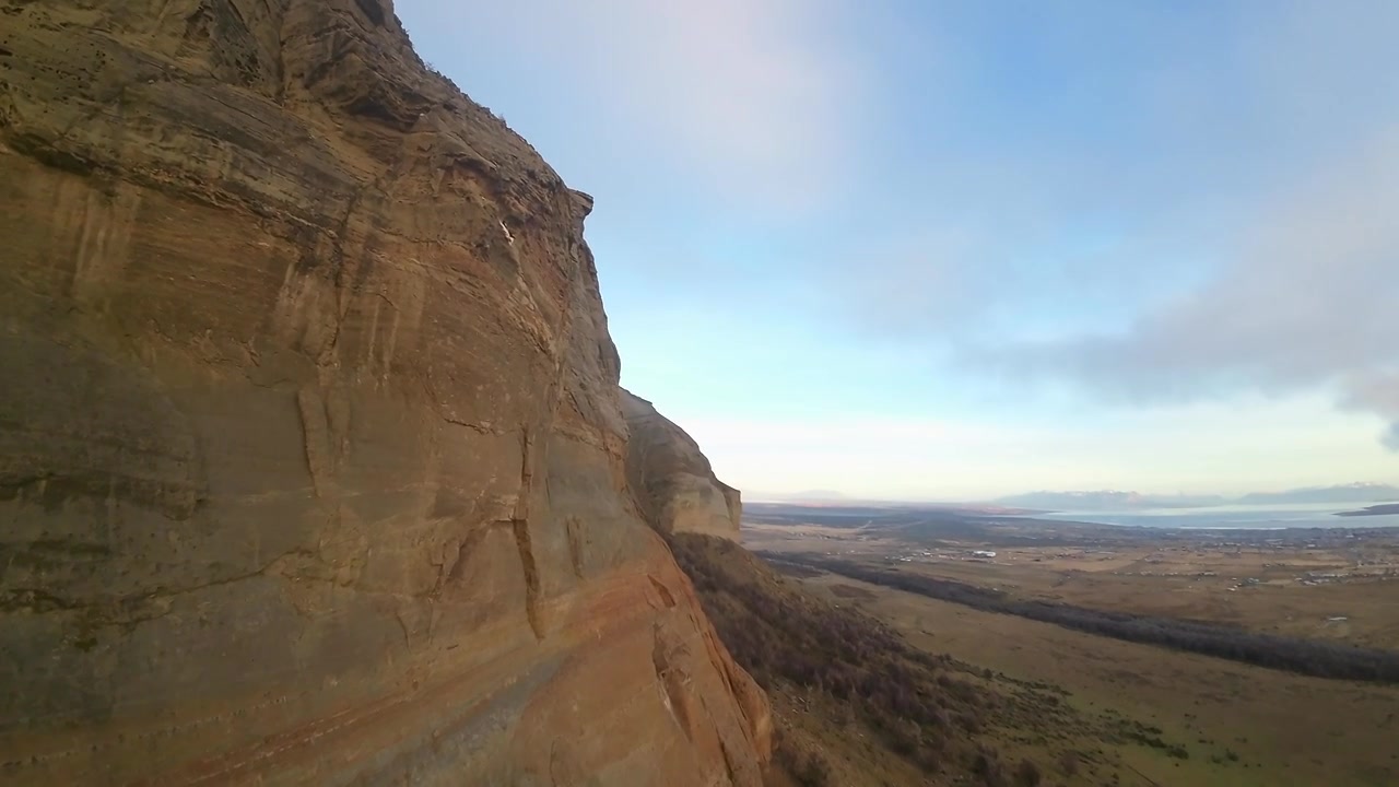 Riprese con drone FPV che sfiorano la imponente parete di arenaria del Cerro Dorotea, affacciandosi su una vasta valle aperta vicino a Puerto Natales, Cile.