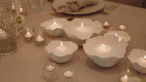 warm candle flames in white bowls create romantic elegant table atmosphere