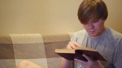 man reading a book on a couch