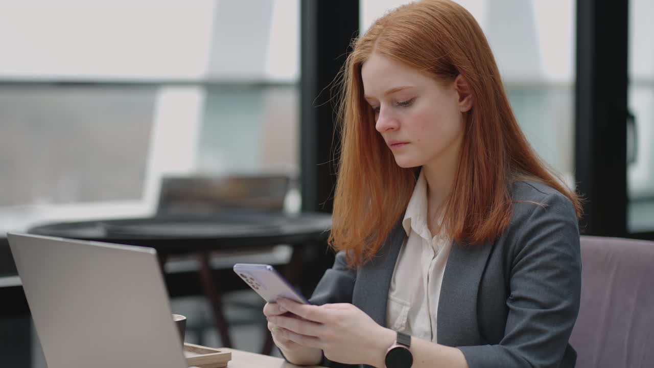 woman is working with laptop remotely in cafe sending message by smartphone and checking notice in mobile phone