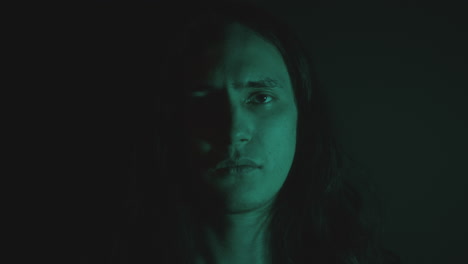 Young Man Opening Eyes and Looking at Camera in Dark Studio