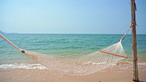 Leere-Hängematte-Am-Sandstrand-Mit-Leichten-Wellen-Und-Endlosem-Horizont