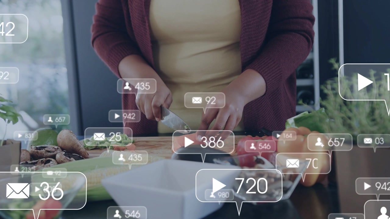 Midlife African American woman cutting veg on counter with knife in cardigan social overlays moving