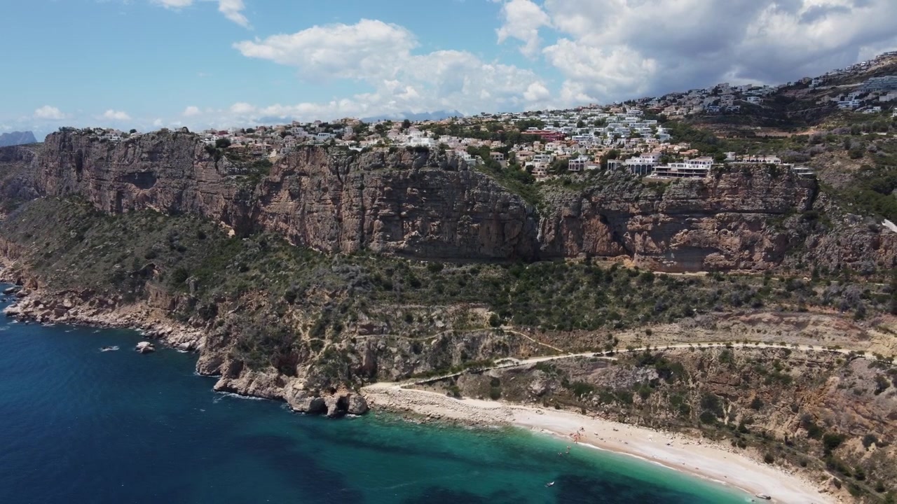 Flyvende væk fra Moraig-bugten, der afslører klipperne med boligudvikling. Benitatxell, Spanien.