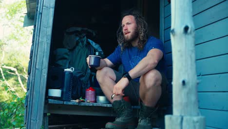 european man drinking coffee in mug at breakfast in cabin