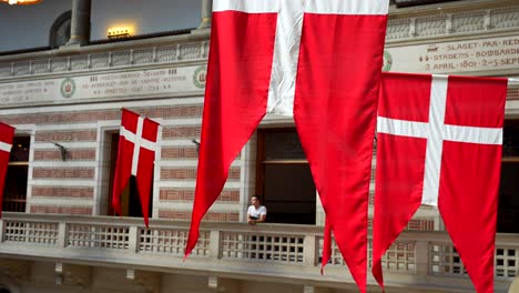 danish flags handing on the city hall of copenhagen, man admiring from balcony