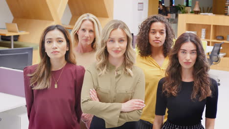 portrait of multi-cultural female business team standing in modern open plan office